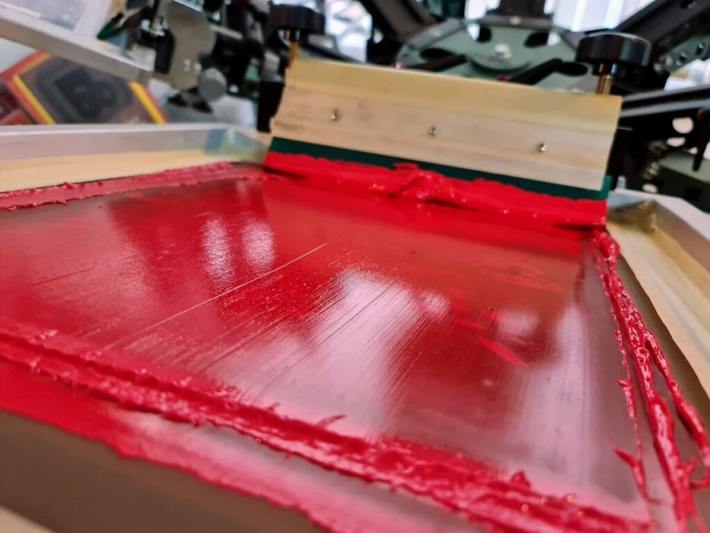 Red screen print with a squeegee in the background